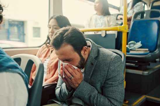 Man sneezing on a bus during his commute
