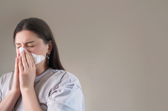 Woman sneezing into tissue
