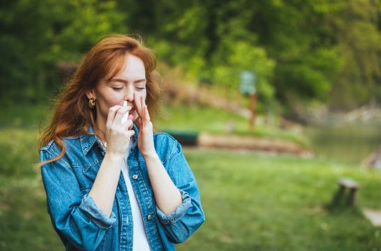 Woman using nasal spray outdoors in a park