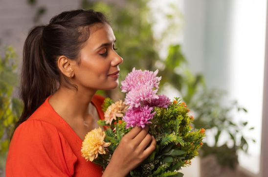 young woman with eyes closed holding flower bouquet and smelling